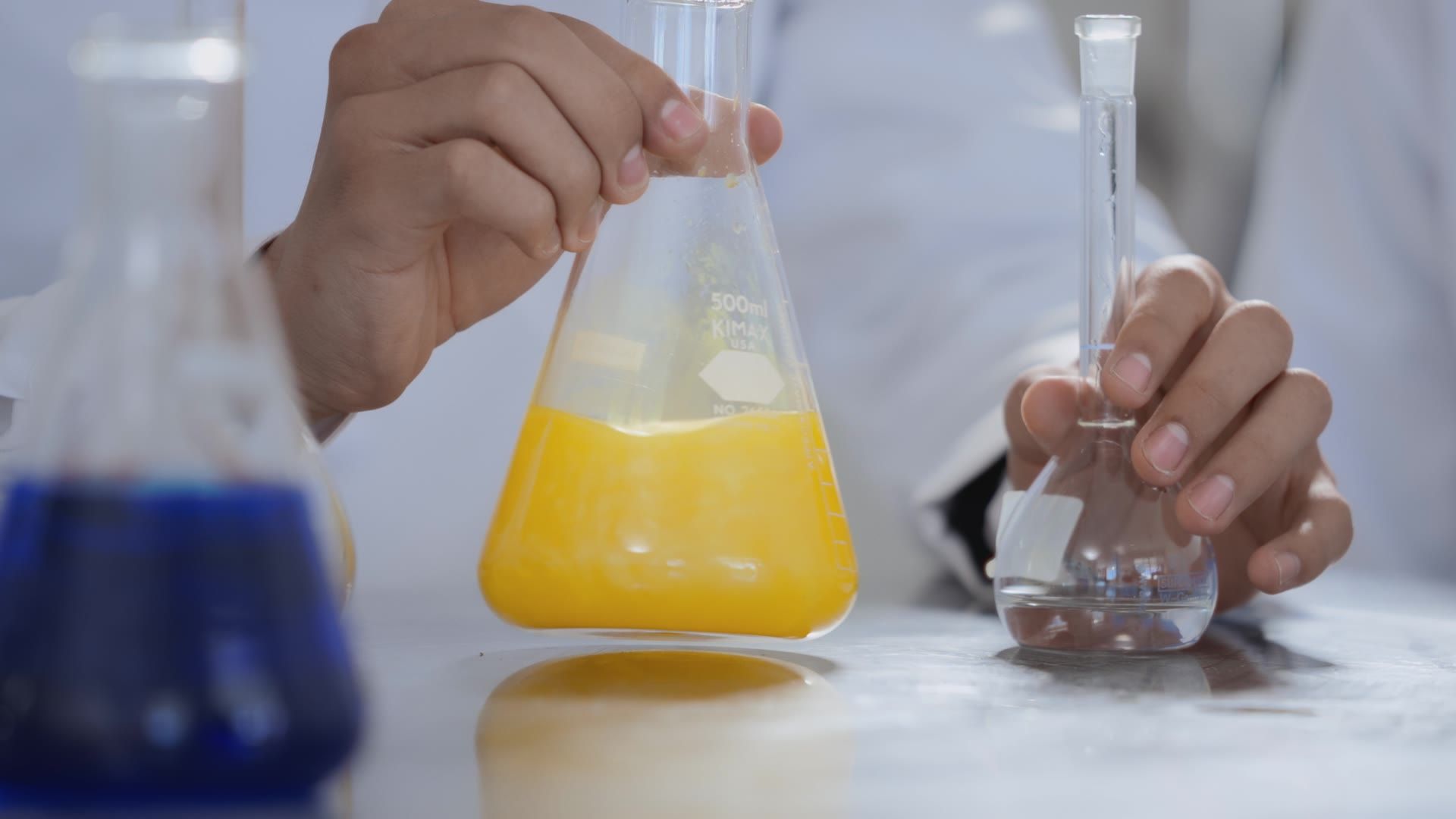 Manos sosteniendo matraces en el laboratorio