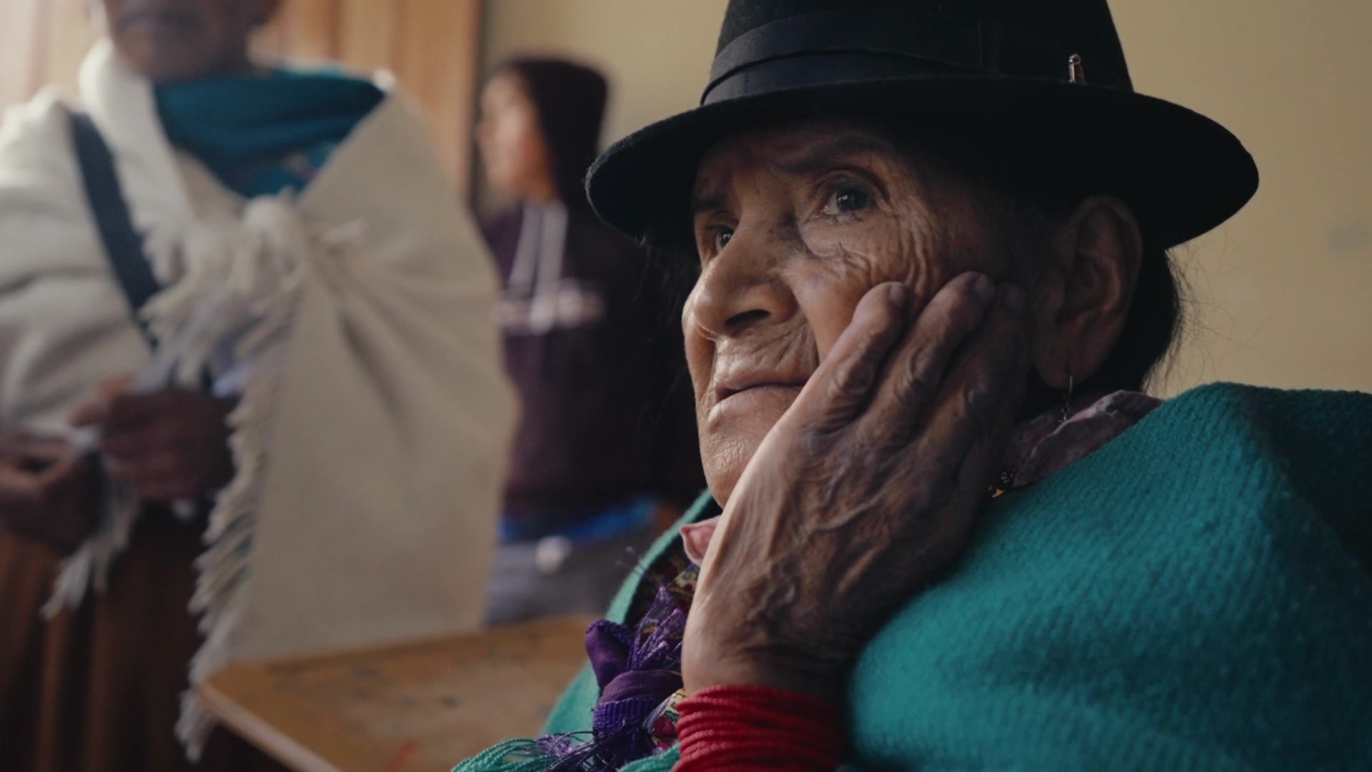 Older Indigenous woman listening with her hand on her face