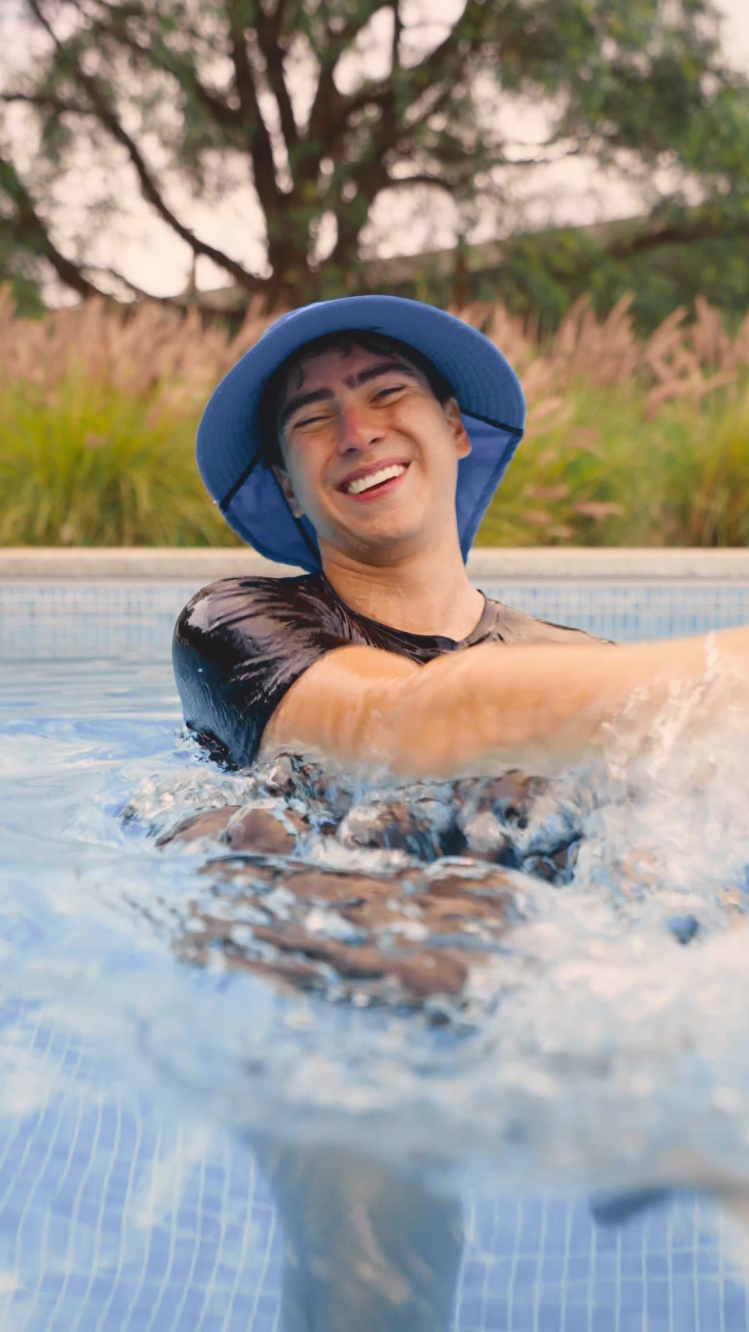 Patas Azules reel: young man in a bucket hat laughing in the pool