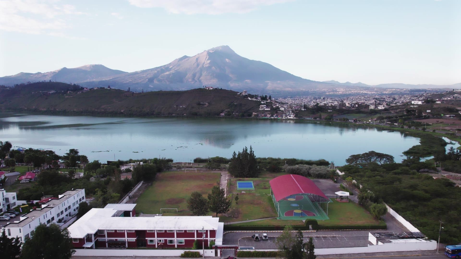 Aerial of the Arrayanes & Álamos campus by the lagoon, with the volcano behind