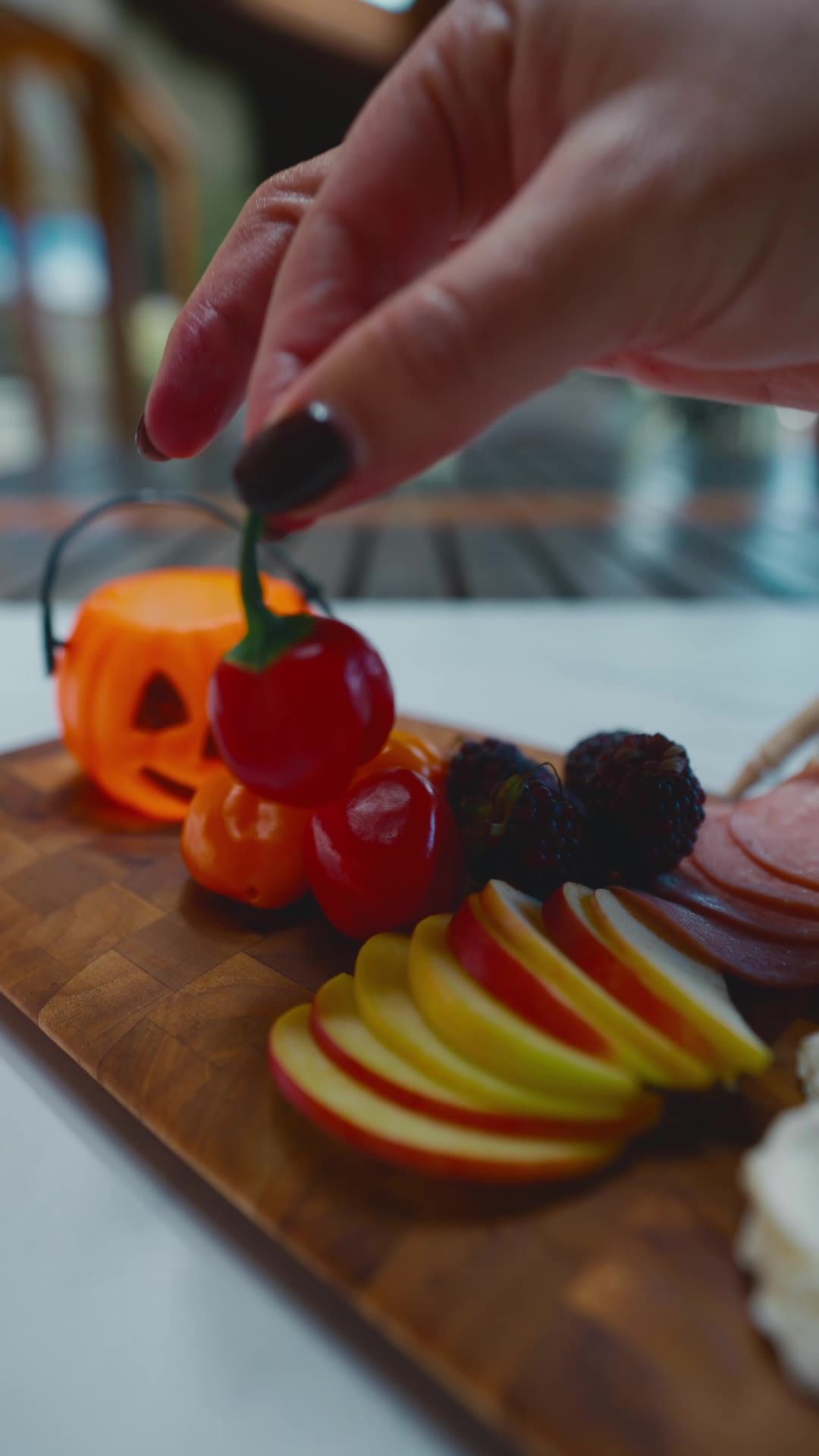 Hand placing a cherry tomato on the board