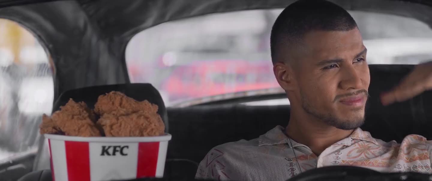 Hombre en su auto con un bucket de KFC en el asiento del copiloto